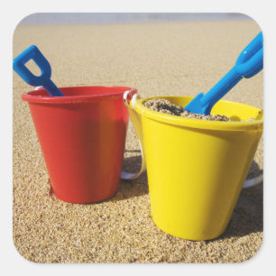 Schaufeln und Eimer auf Sandy-Strand Quadratischer Aufkleber
