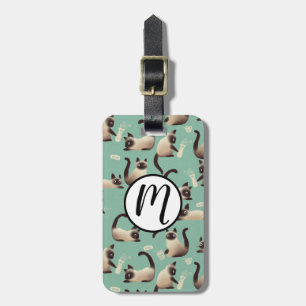 Schlechte siamesische Katzen klopfen über Gepäckanhänger