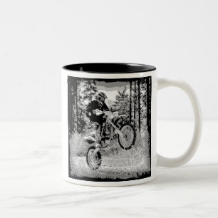 Schmutzfahrrad, das in das Holz sich dreht Zweifarbige Tasse
