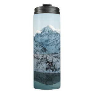 SCHNEEBEDECKTER BERG NAHE EINEM GEWÄSSER THERMOSBECHER