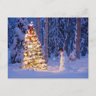 Schneemann und Weihnachtsbaum an einer Winternacht Feiertagspostkarte