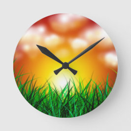 Schöner Sonnenaufgang über einem Grasfeld Runde Wanduhr