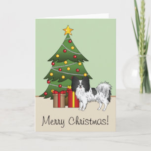 Schwarz-weißer Papillon-Hund an einem Weihnachtsba Karte