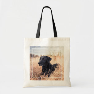 Schwarzer Labrador in trockenem Gras Tragetasche