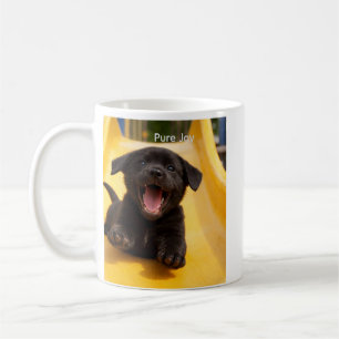 Schwarzer Labrador Retriever glücklicher Welpe auf Kaffeetasse