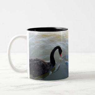 Schwarzer Schwan wird von Riesenfischen angegriffe Zweifarbige Tasse