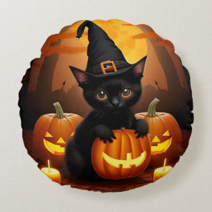 Schwarzes Kätzchen in Hexenhut zwischen Halloween- Rundes Kissen
