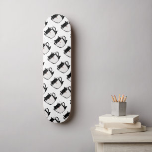 Schwarzes Kätzchen mit roter Nase, das sich in ein Skateboard