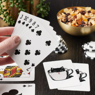 Schwarzes Kätzchen mit roter Nase, das sich in ein Spielkarten