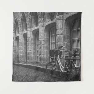 SCHWARZWEISS-FOTO EINES FAHRRADS, DAS NEBEN EINEM  WANDTEPPICH