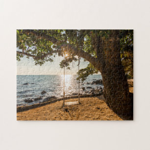 Schwingen auf dem Strand am Sonnenuntergang