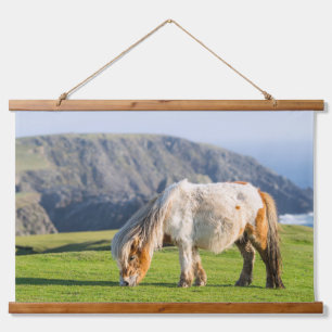 Shetlandpony auf einer Weide nahe hohen Klippen Wandteppich Mit Holzrahmen