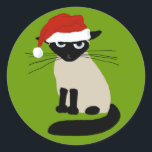 Siamese Santa Clause - Funny Christmas Cat Runder Aufkleber<br><div class="desc">Grouchy Siam Cat Holiday Stickers. Die lustige Katze trägt einen Weihnachtshut. Dieses verärgerte Kätzchen sagt Bah Humbug, einen lächerlichen Hut zu tragen. Diese lustigen Aufkleber eignen sich perfekt, um die Rückseite der Urlaubshüllungen zu schließen. Besuchen Sie Jenn’s Doodle World für lustigere Katzenfreunde-Produkte und coole Geschenke mit diesem humorvollen Xmas Cat...</div>