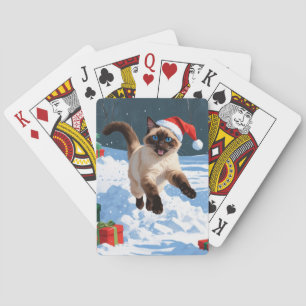 Siamische Katze läuft im Schnee mit Weihnachtsmütz Spielkarten