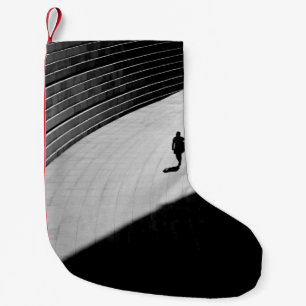 SILHOUETTE EINER PERSON, DIE AUF DER GRAUEN KONKRE KLEINER WEIHNACHTSSTRUMPF