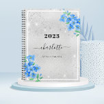 Silver blue floral name Termin 2024 Planer<br><div class="desc">Ein Imitat silber metallisch aussehender Hintergrund,  mit blauen vergessenen-nicht-floralen,  Blume. Imitate Glitzer Staub. Personalisieren und fügen Sie ein Jahr,  Name und Titel.</div>