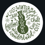 Snowman Christmas Winter Wonderland Typografie Runder Aufkleber<br><div class="desc">Eine festliche typografische Komposition von handgeschriebenem Weihnachtszitat (Schneekill, Steinglocken, Kalter Winter, Weiße Weihnachten, Wunderland, Weihnachtswunsch) umkreist einen Schneemann mit kleinen Herzen und Schneeflocken. Ideal, um Weihnachts- und Feiertagsbriefe und Weihnachtskarten zu Siegel oder Ihre Geschenke unter dem Weihnachtsbaum zu schmücken! Forest Green Farbe ist vollständig veränderbar, auch die Farbe Weiß ist...</div>