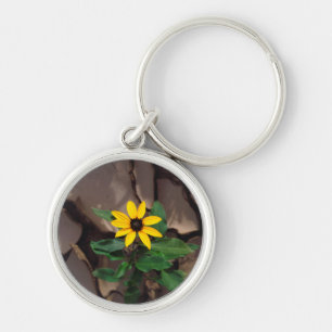 Sonnenblume wächst aus aufgesprungenem Schlamm Schlüsselanhänger