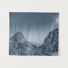 Sonnenlicht und dunkle Wolken über schneebedeckten Wandteppich