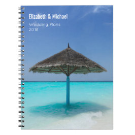 Sonnenschirm aus Strohdach auf Hochzeitsplänen von Notizblock