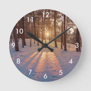 Sonnenuntergang im schneebedeckten Kiefernwald Runde Wanduhr