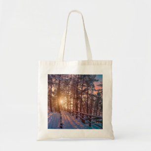 Sonnenuntergang im schneebedeckten Pinienwald mit Tragetasche