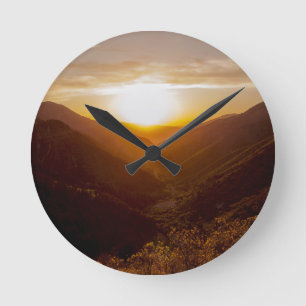 Sonnenuntergang über der Berglandschaft Runde Wanduhr