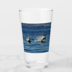 Spielende Gewöhnliche Delfine springen durch den O Glas
