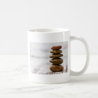 Stapel der Dunkelheit färbte Steine auf weißem Kaffeetasse
