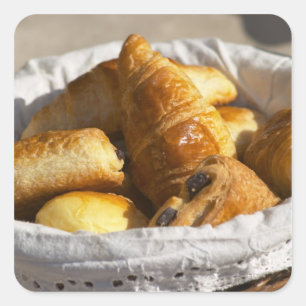 Sticker Carré Un panier petit-déjeuner en osier avec croissants.