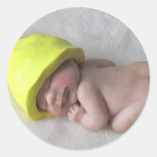 Sticker Rond Bébé d'argile dormant sur le ventre, casquette
