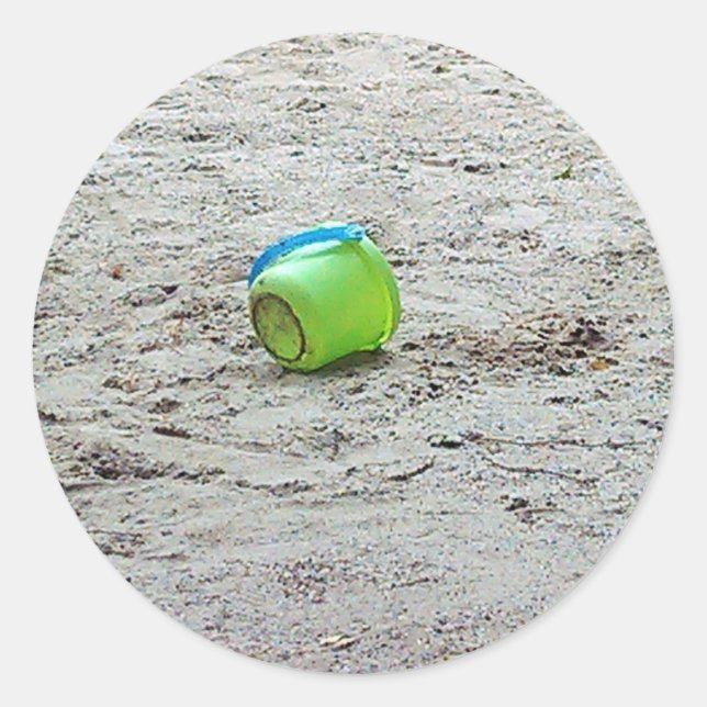 Sticker Rond Bouche verte perdue dans le sable sur la plage d'é (Devant)