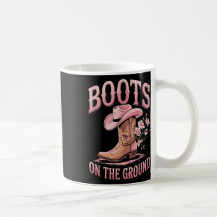 Stiefel auf dem schwarzen Western am Boden, wo die Kaffeetasse