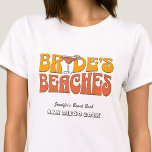 Strand Junggeselinnen-Abschied Groovy Bride's Beac T-Shirt<br><div class="desc">Lassen Sie sich mit diesem atemberaubenden Junggeselinnen-Abschied am Strand, personalisierten T - Shirt, von Ihrem bevorstehenden Junggeselinnen-Abschied verwöhnen. Ob Sie einen Badeurlaub, einen Mädchenurlaub oder einen Junggeselinnen-Abschied der besten Freunde verbringen möchten, diese T - Shirt sind die perfekte Ergänzung zu Ihrem unvergesslichen Aufenthalt. Fügen Sie Ihrem Junggeselinnen-Abschied eine persönliche Touch...</div>