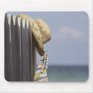 Strohhut, der am Zaun am Strand hängt Mousepad