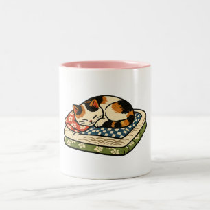 Süße schlafende Dreifarbenkatze auf traditionellem Zweifarbige Tasse