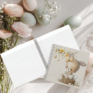 süßes Kaninchen mit Ostereiern auf einer Blumenwie Notizbuch