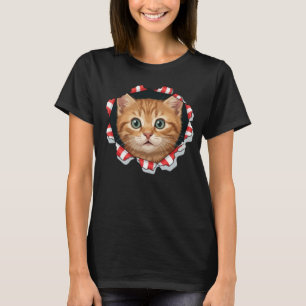 Süßes Kätzchen schaut durch zerrissenes Gewebe T-Shirt