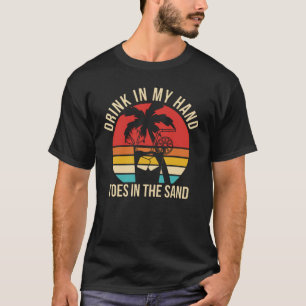 T-shirt boire dans mes orteils à la main dans le sable