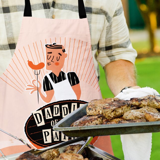 Tablier Drôle Grill Apron pour papa, Daddio du Patio (Man outside wearing a "Daddio of the patio apron" while grilling and holding a large platter of meat)