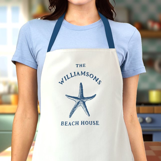 Tablier Maison de plage de Starfish Côte Bleue Personnalis (Woman in a kitchen wearing a white apron with a blue starfish design and The Williamsons Beach House)