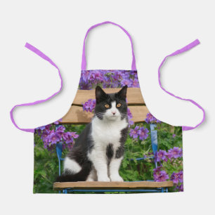 Tablier Tuxedo cat sitting on a garchair with flowers