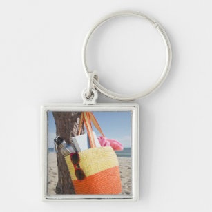Tasche, die am Baum-Stamm an Sandy-Strand hängt Schlüsselanhänger
