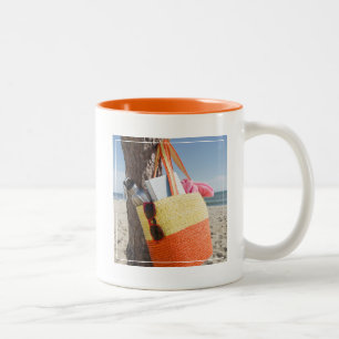 Tasche, die am Baum-Stamm an Sandy-Strand hängt Zweifarbige Tasse