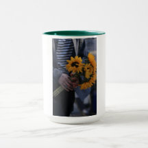 Tasse blanche où une main tient des tournesols ave