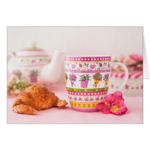 Tasse mit Tee, Croissant und Blume