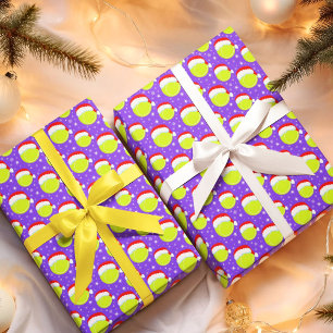 Tennisbälle tragen Santas Hut und Schneeflocken in Geschenkpapier