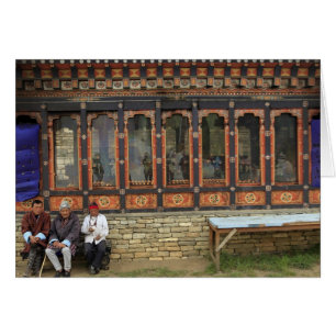 Three men sit on a bench at the Memorial Chorten