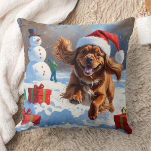 Tibetischer Spaniel läuft im Schnee mit Weihnachts Kissen