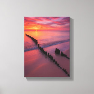 Toile Coucher de soleil sur la plage avec des poteaux en